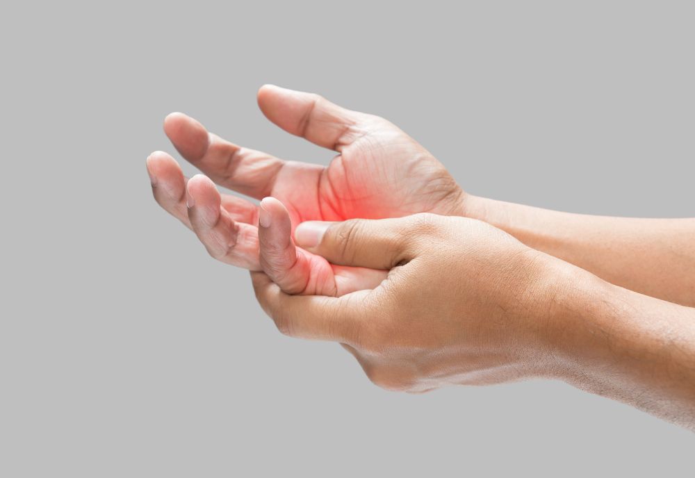 Two hands, with one gently cradling the other, show a red area indicating discomfort or pain in the palm.