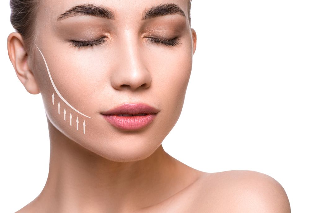 A woman with closed eyes exhibits white arrows and a curved line on her cheek against a white background, illustrating a facial contour concept—a nod to modern cosmetic procedures.