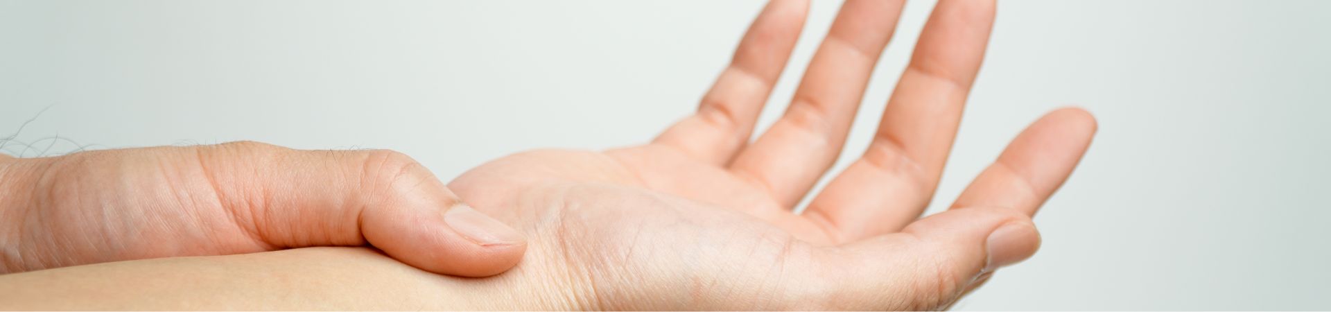 Close-up of a hand with fingers slightly spread, resting on a light surface.