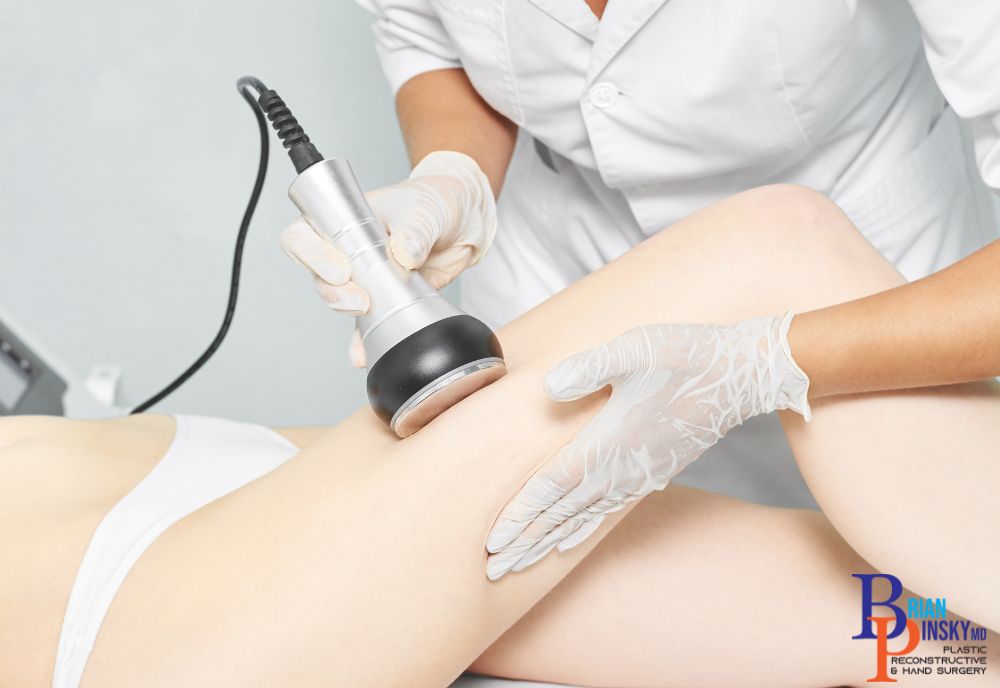 A professional, wearing gloves, performs a cosmetic body contouring procedure on a client's thigh using a handheld device.