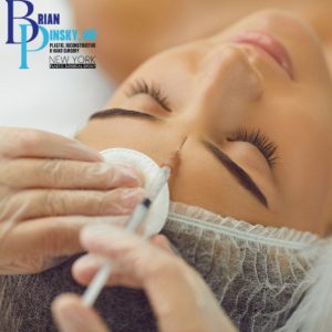 A person is peacefully lying down, receiving a Botox injection on the forehead, wearing a cap. Gloves and a cotton pad are visible, ensuring precision and care. A logo graces the corner, representing professional expertise in cosmetic procedures.