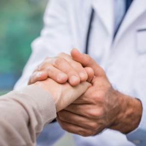 A hand specialist on Long Island, wearing a white coat, gently holds a patient's hand, conveying support and reassurance.