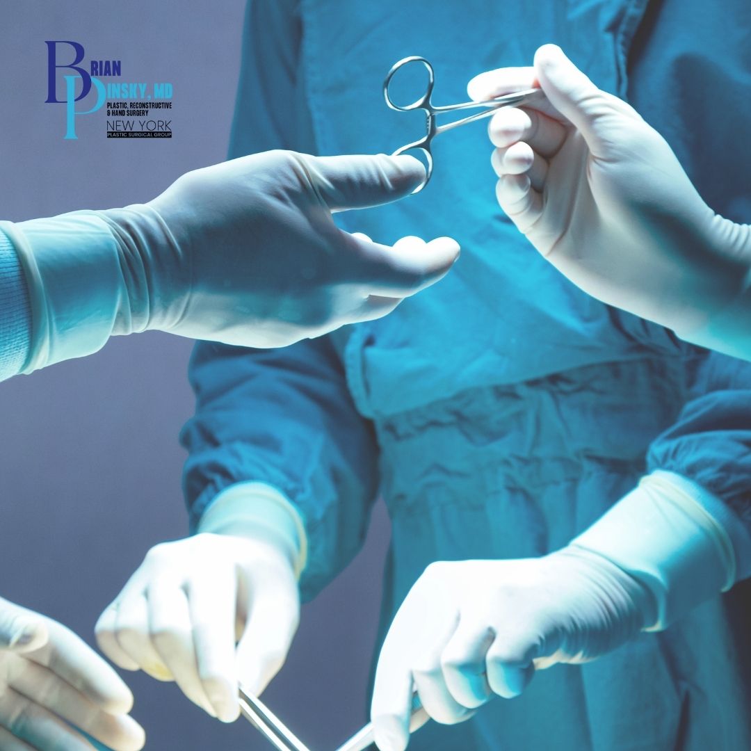 Three gloved hands in surgical attire pass medical instruments in an operating room. The logo "Brian Pinsky, MD, Hand Surgeon, Plastic Surgery, Long Island, New York" is visible in the upper left corner. Three gloved hands in surgical attire pass medical instruments in an operating room The logo "Brian Pinsky, MD, Hand Surgeon, Plastic Surgery, Long Island, New York" is visible in the upper left corner